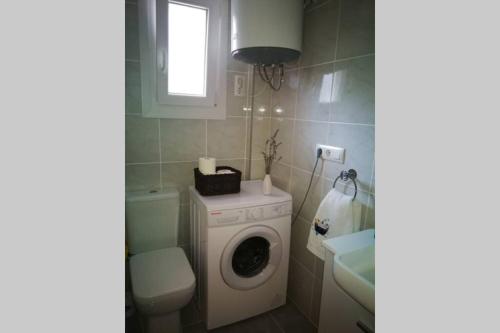 a bathroom with a washing machine and a toilet at Acogedor apartamento en la zona de las Fuentes con WiFi in Alcossebre