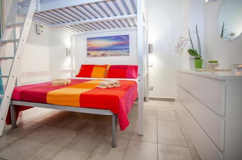 una camera bianca con un letto con un copriletto colorato di Casa Gioia a Giardini Naxos
