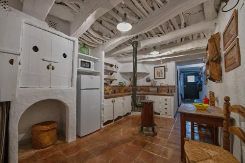 a large kitchen with a fireplace and white cabinets at Casa La Romanilla in Capileira
