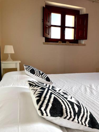 a white bed with two pillows on it with a window at La Vecchia Fornace in SantʼAnna Arresi