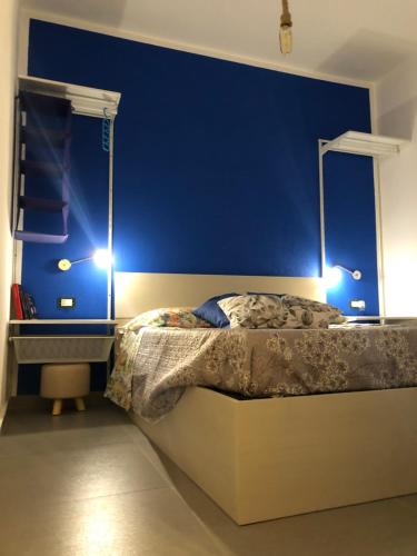 a bedroom with blue walls and a bed with two lights at La Pedrosa 83 in Scalea