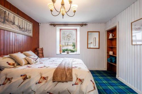 a bedroom with a bed and a chandelier at Meadowhead Cottage, Traditional Scottish Cottage in Waterside