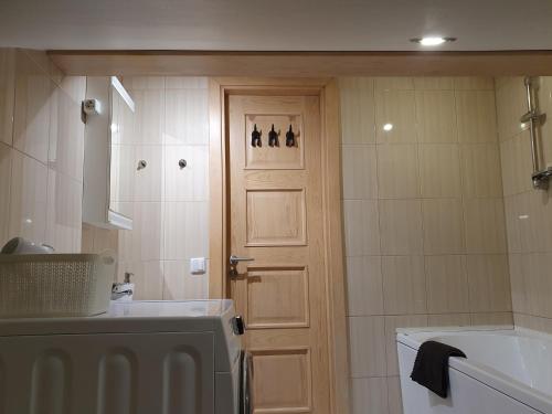 een badkamer met een deur, een wastafel en een bad bij KK Apartment city in Ventspils