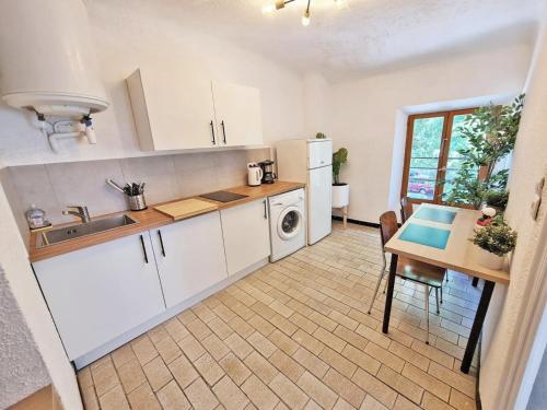 une cuisine avec des armoires blanches, une table et un évier dans l'établissement GregBnb - T2 Design 34m2 - Toulon Est - Wifi Fibre - n9, à Toulon