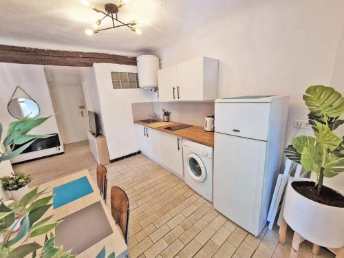 een keuken met een witte koelkast en een tafel met een plant bij GregBnb-com - T2 Design 34m2 - Toulon Est - Wifi Fibre - n9 in Toulon