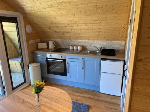 uma cozinha com armários azuis e um tecto de madeira em Volcano Cabins em Acharacle