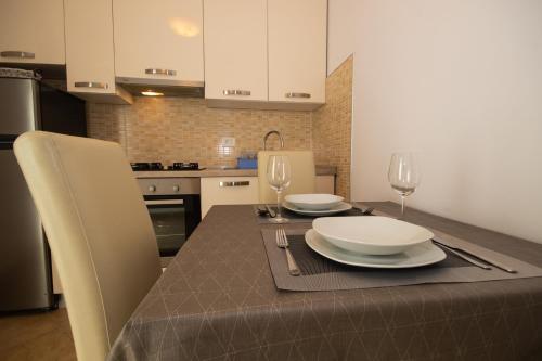 a kitchen with a table with two plates and wine glasses at zdenka in Rabac