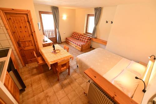 a bedroom with a bed and a table and a couch at Residence Raethia tra Bormio e Livigno in Valdidentro