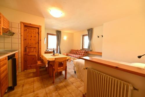 a kitchen with a table and a living room at Residence Raethia tra Bormio e Livigno in Valdidentro
