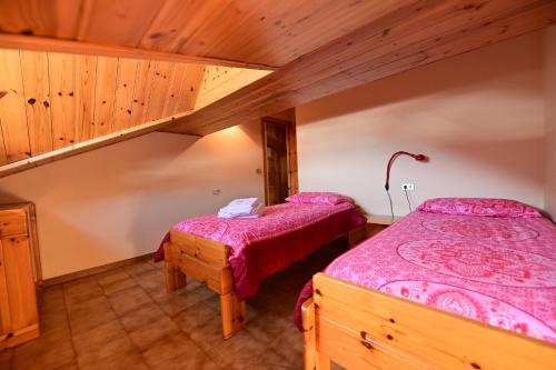 two beds in a room with wooden ceilings at Residence Raethia tra Bormio e Livigno in Valdidentro