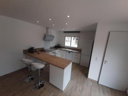 une grande cuisine blanche avec un comptoir et des tabourets dans l'établissement Villa_Culomba ALATA -T2 4 couchages, à Alata