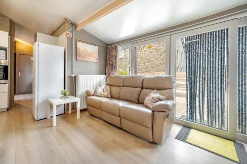 a living room with a couch and a large window at Le préau, honden vriendelijke huisje in Ardennen in La Roche-en-Ardenne