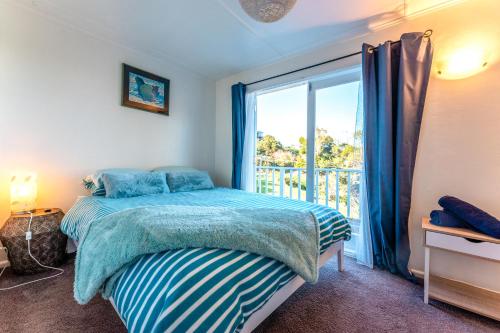 a bedroom with a bed and a large window at The Butterfly Bach - Surfdale Holiday Home in Surfdale