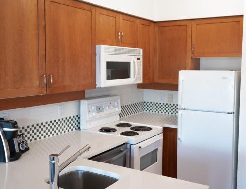 a kitchen with white appliances and wooden cabinets at Alpenglow Lodge by MVA in Whistler