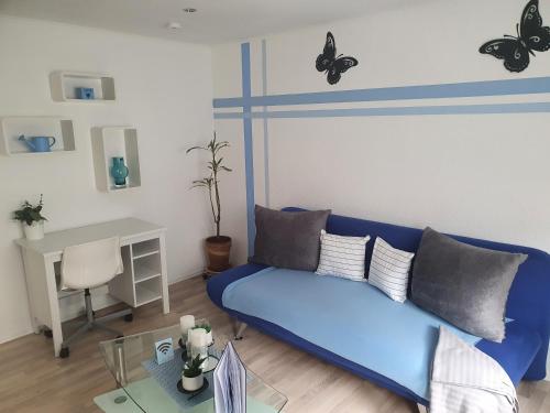 - un canapé bleu dans un salon avec des papillons sur le mur dans l'établissement Ella's Wolke Appartements - EW3, à Zweibrücken