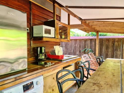 a kitchen with a table and chairs and a microwave at Pension Les Trois Cascades in Uturoa