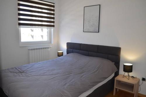 uma cama num quarto com uma janela e uma cama sidx sidx em Comfy New Apartment em Sarajevo