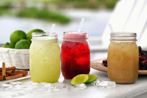 tres jarras de albañil llenas de diferentes bebidas de colores en una mesa en Maya Internacional, en Flores