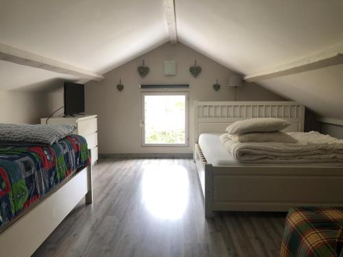 1 dormitorio en el ático con 2 camas y ventana en Chambon-sur-Lac en Chambon-sur-Lac
