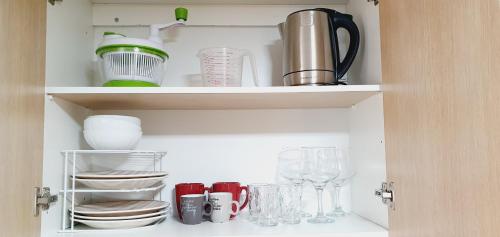 a cupboard filled with dishes and wine glasses at kelly's House Plateau City Center in Praia