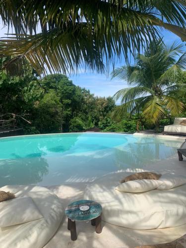 a large swimming pool with pillows and a table at La Cabane in Jimbaran