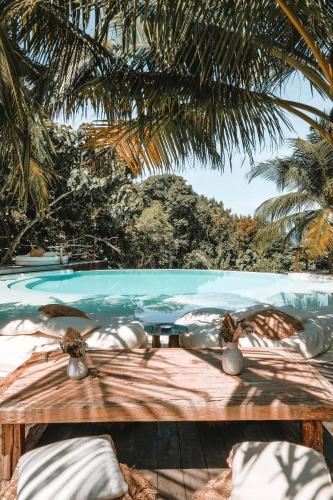a view of a swimming pool with a wooden bench at La Cabane in Jimbaran