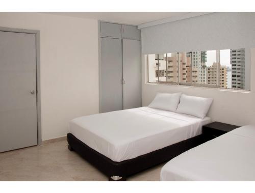 ein weißes Schlafzimmer mit 2 Betten und 2 Fenstern in der Unterkunft III NICE 2 BEDROOM APARTMENT Bocagrande in Cartagena de Indias