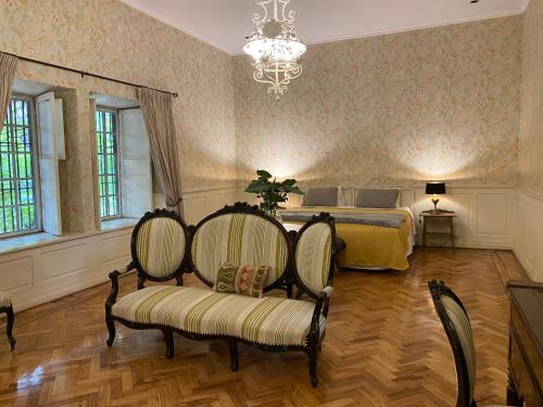 a bedroom with a bed and two chairs and a chandelier at Casona Lo Aguirre , Hospedaje de Temporada Cálidas in Talagante