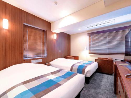 a hotel room with two beds and two windows at Central Hotel Okayama in Okayama
