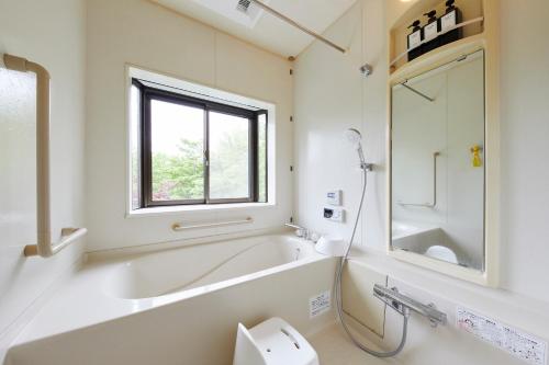 a bathroom with a tub and a toilet and a window at 湖の辺の宿時翠 in Yamanakako