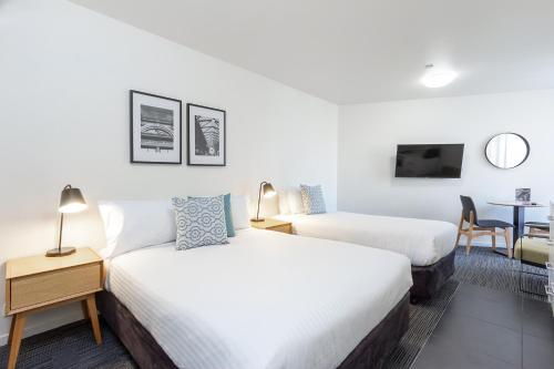 Habitación de hotel con 2 camas y mesa en City Edge North Melbourne Apartment Hotel, en Melbourne