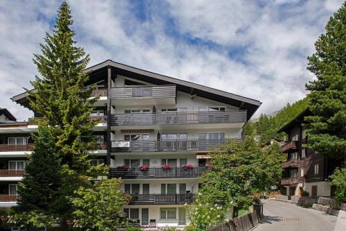 an apartment building with balconies and trees at Mountain Apartments Zermatt Studio Nr 4 in Zermatt