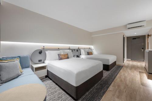 a hotel room with two beds and a couch at Crowne Plaza Hawkesbury Valley by IHG in Windsor