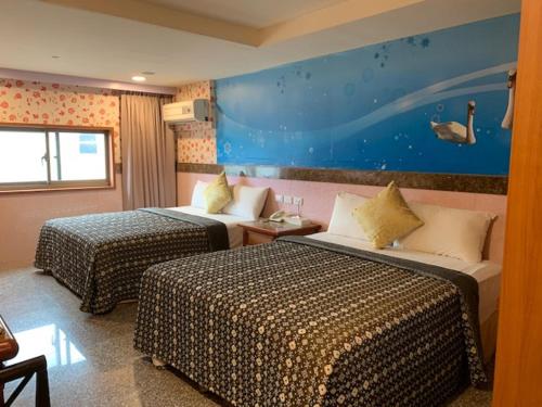 a hotel room with two beds and a painting on the wall at Yi Pin Business Hotel in Taoyuan
