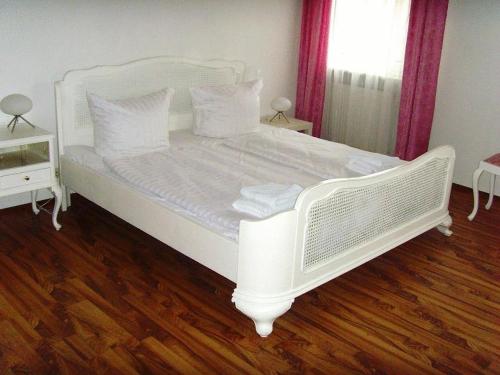 Cama blanca en habitación con suelo de madera en Hotel Schlossberg en Heppenheim an der Bergstrasse