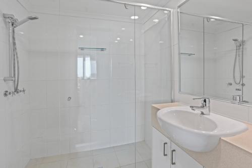 a white bathroom with a shower and a sink at Spectrum Holiday Apartments in Gold Coast