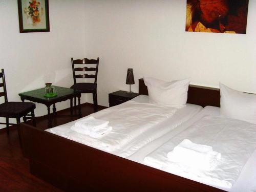 a bedroom with a white bed with two chairs and a table at Hotel Schlossberg in Heppenheim an der Bergstrasse