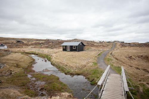 une petite maison noire sur une colline avec une route dans l'établissement Luxury Cottage in Tórshavn, à Tórshavn