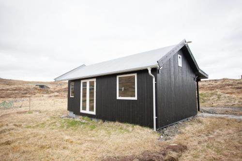 Czarny dom na wzgórzu z polem w obiekcie Luxury Cottage in Tórshavn w mieście Torshavn