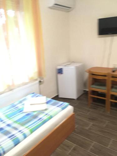 um quarto com uma cama, uma mesa e um frigorífico em Vasmacska Panzió em Komárom