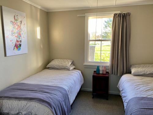 2 łóżka pojedyncze w pokoju z oknem w obiekcie The Cottage @ Aranui w mieście Wairoa