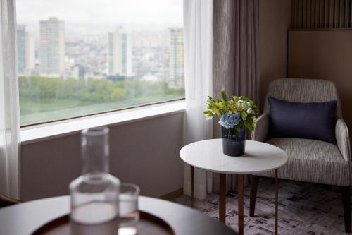a room with a vase of flowers on a table and a window at Lotte Hotel World in Seoul