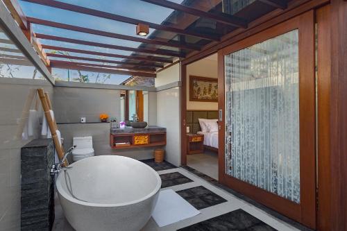 a bathroom with a bath tub and a bedroom at Alam Wayang Ubud - CHSE Certified in Ubud