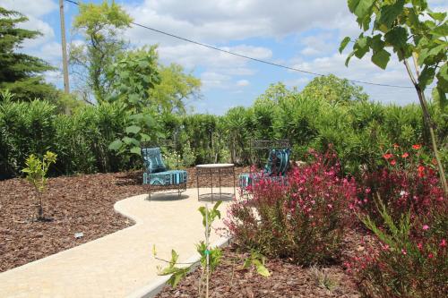 a garden with two chairs and a table and flowers at B&B Casa do Cerro in Moncarapacho