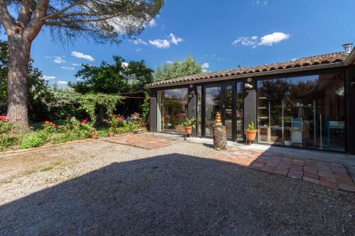 a house with glass doors and a tree at B&B du Couvent, vue château in Giroussens
