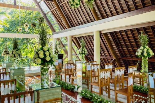 a banquet hall with tables and chairs and flowers at Komaneka at Bisma Ubud in Ubud