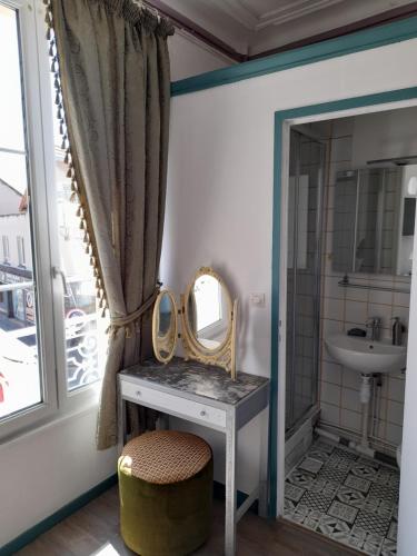 a bathroom with a vanity with a mirror and a sink at Le DINGSON in Arromanches-les-Bains