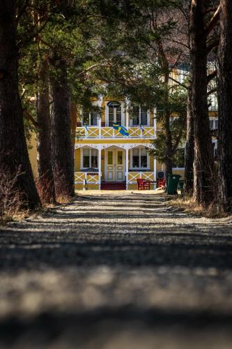 a yellow house with trees in front of it at Hammarstrand B&B och lägenhet in Hammarstrand