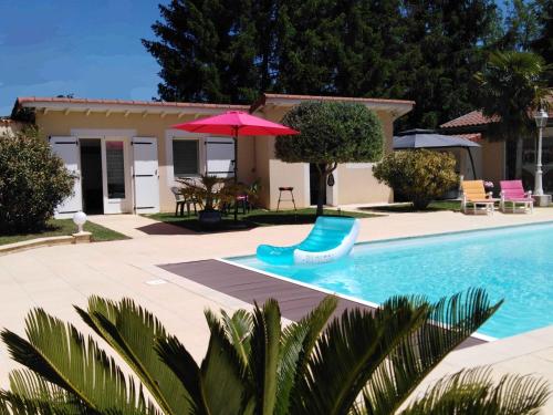 - une piscine avec un parasol rouge et une chaise dans l'établissement CoeurAccords, spa & bien-être au calme NATURISTE toute l'année, à Saint-Bardoux