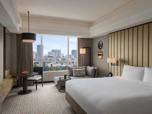 ホーチミン・シティにあるニュー ワールド サイゴン ホテルの大きなベッドと窓が備わるホテルルームです。